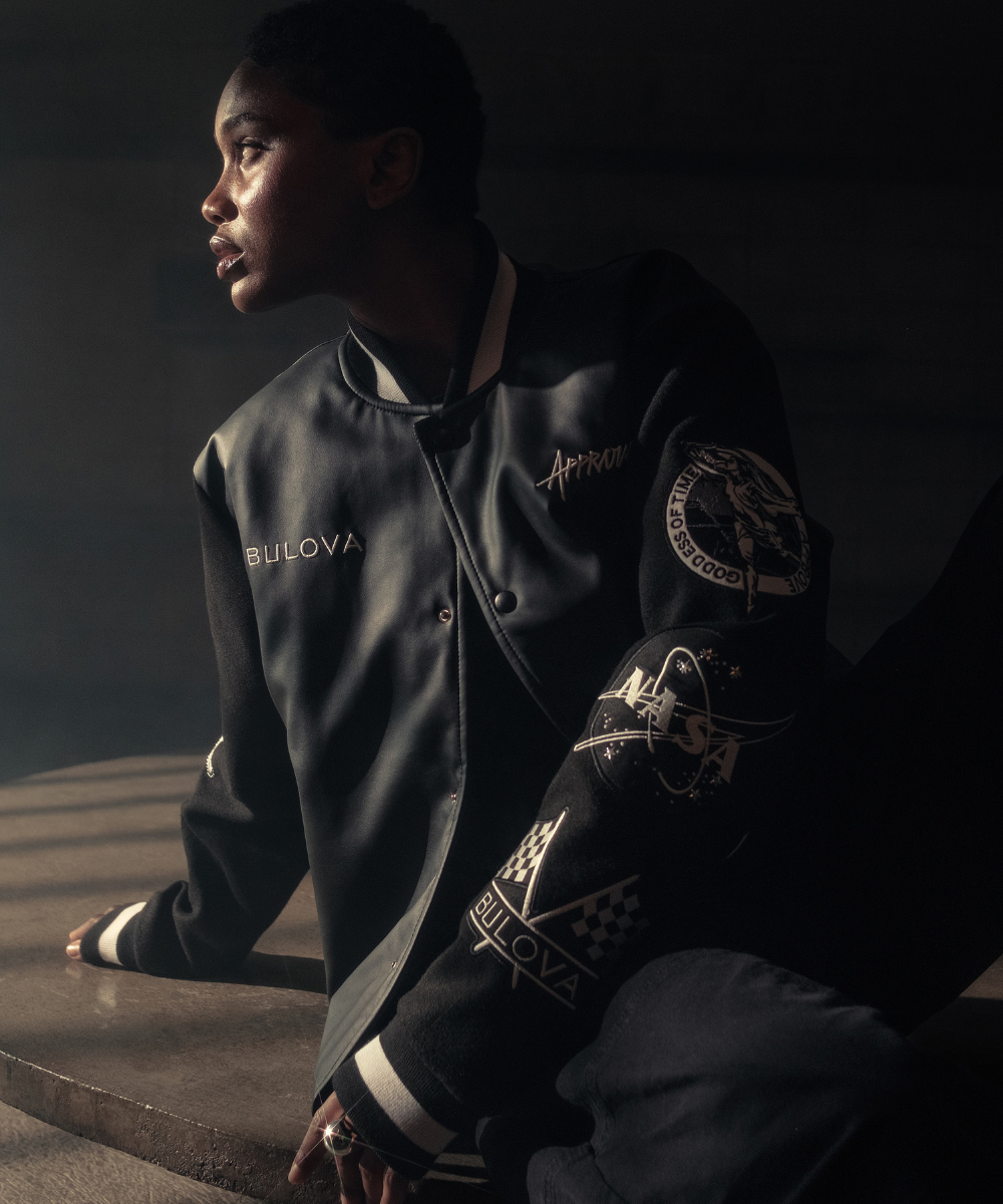Pessoa com jaqueta estilizada com logos e emblemas, simbolizando novidades de moda urbana.