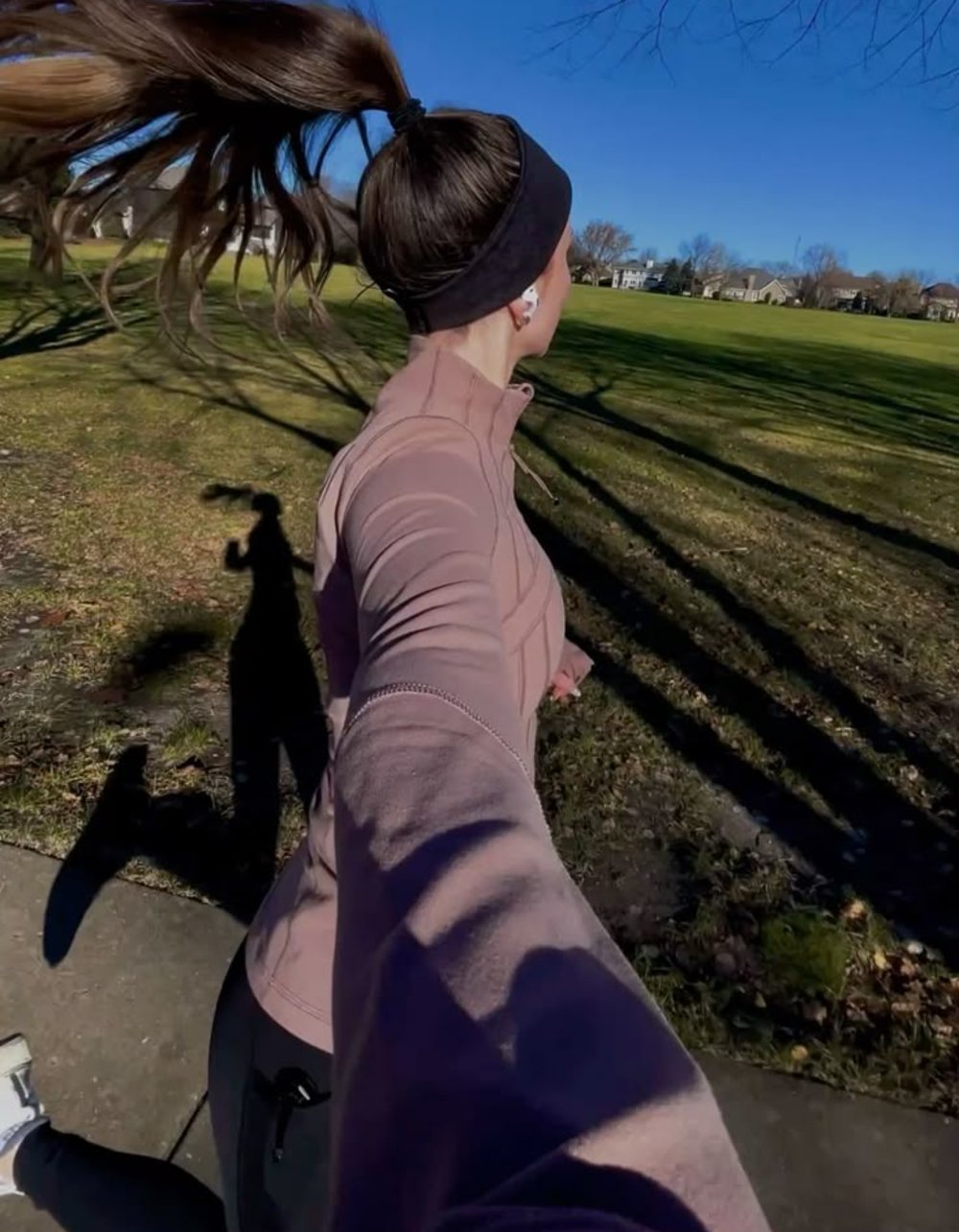 Correndo em um parque, vestindo roupas para correr no frio, uma pessoa veste casaco e faixa na cabeça.