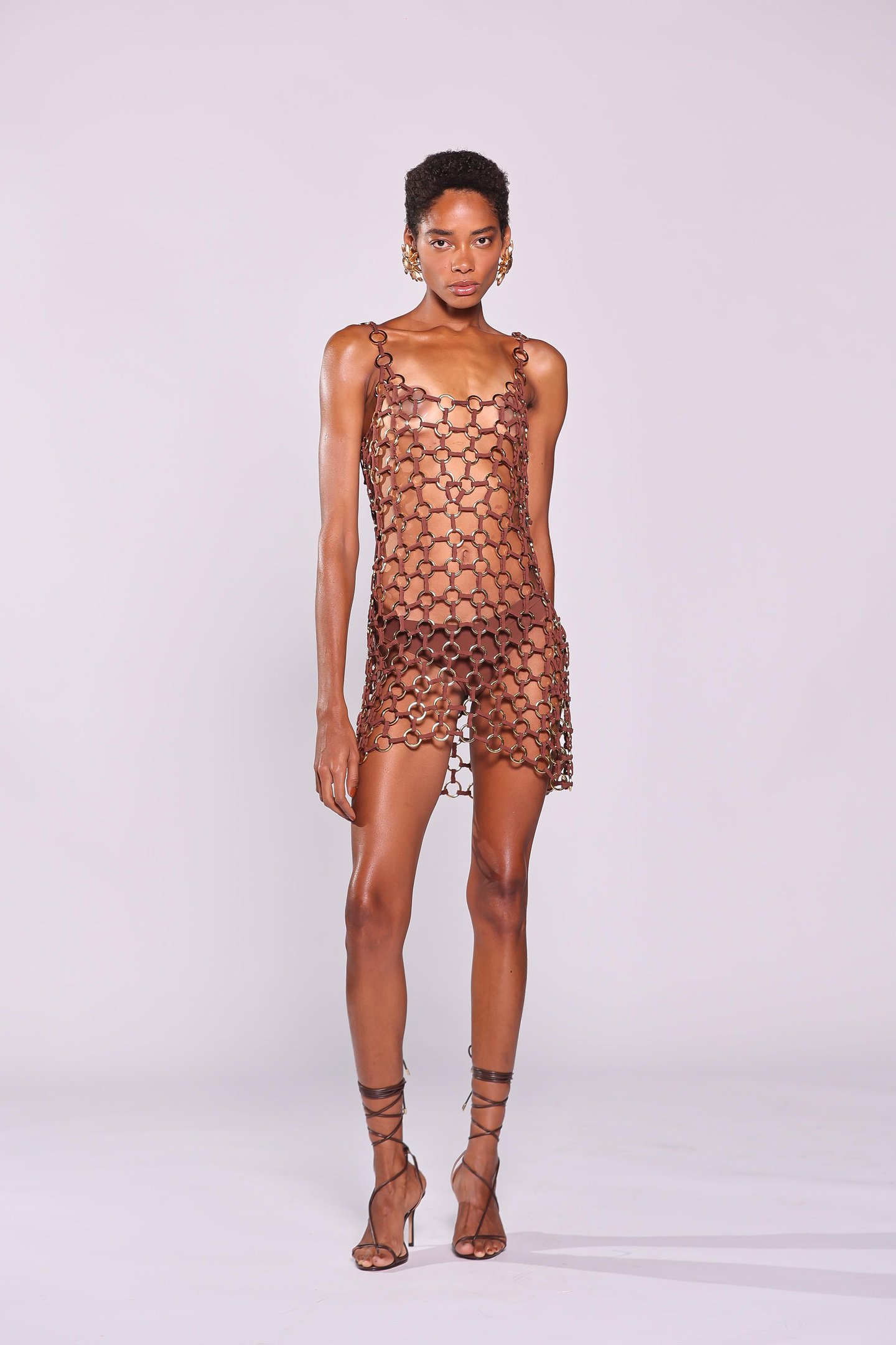 Modelo usando vestido de corrente marrom, tendência de verão, com salto alto de tiras.
