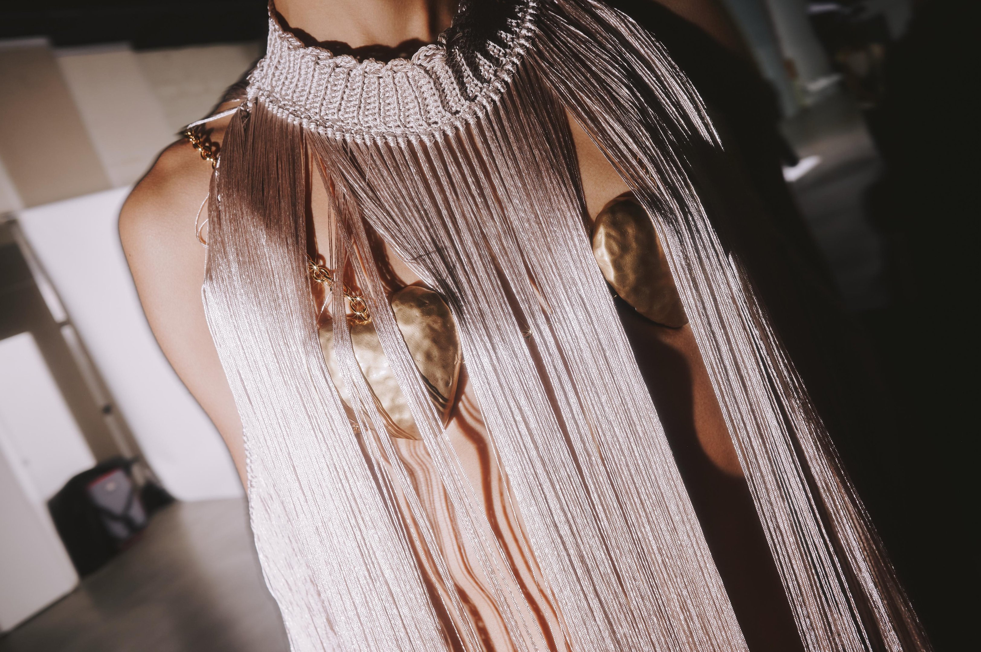 Vestido de franja metálico com detalhes dourados, refletindo tendências de verão.