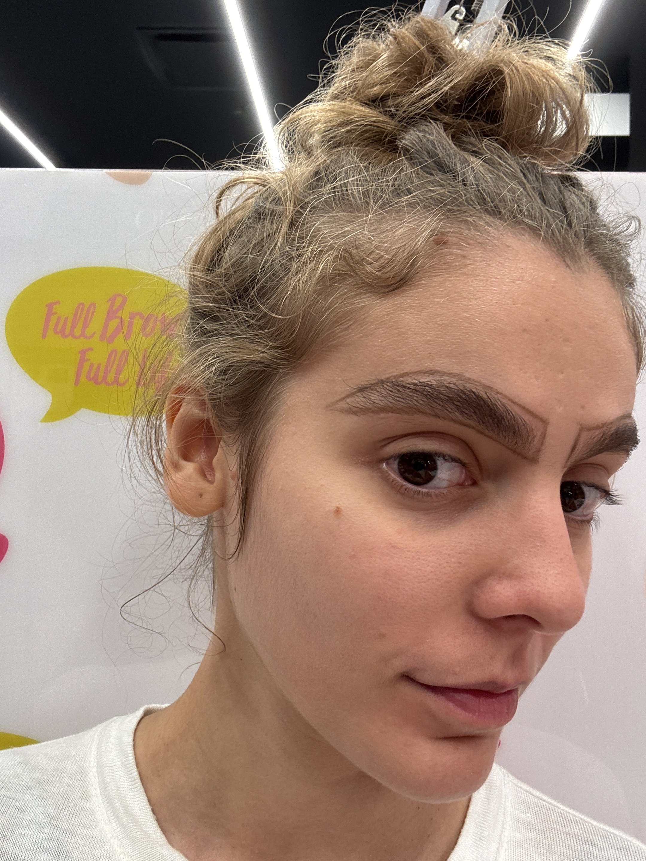 Mulher de cabelo preso em coque, destacando sobrancelha grossa e bem definida.