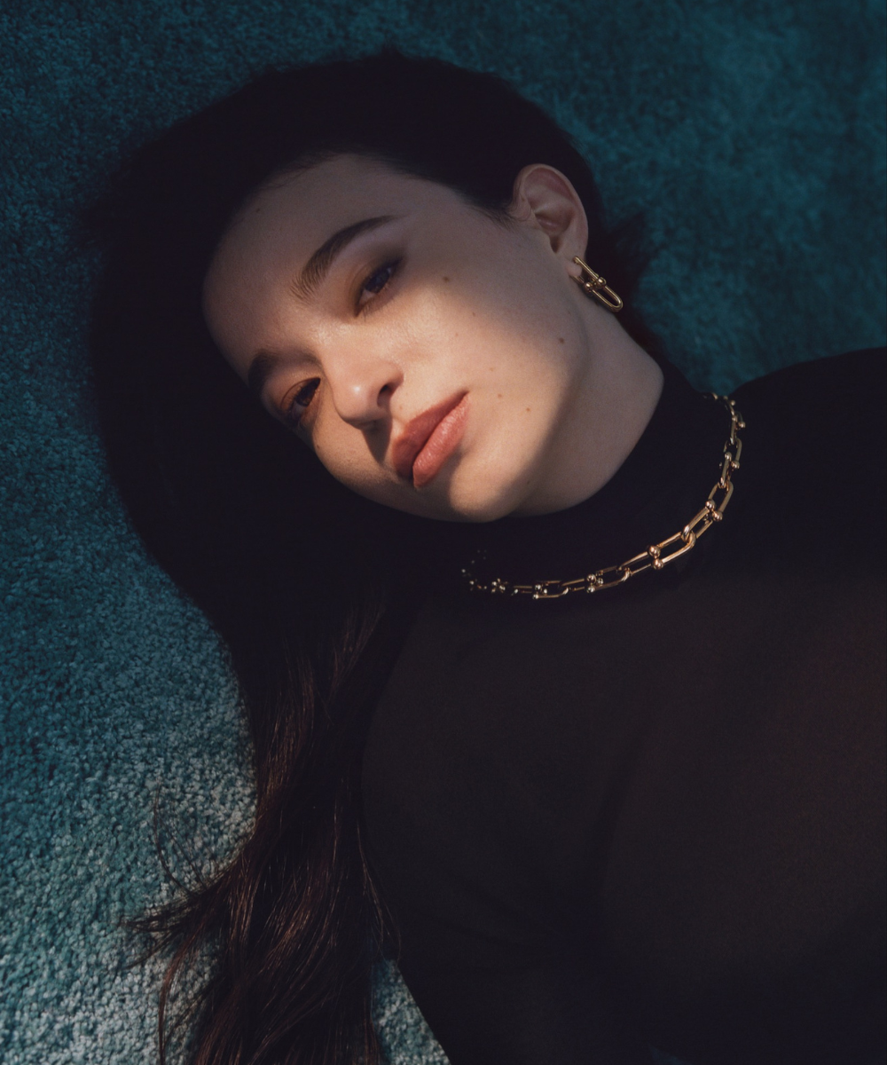 Uma mulher com colar e brincos dourados, tendência nas novidades de moda.