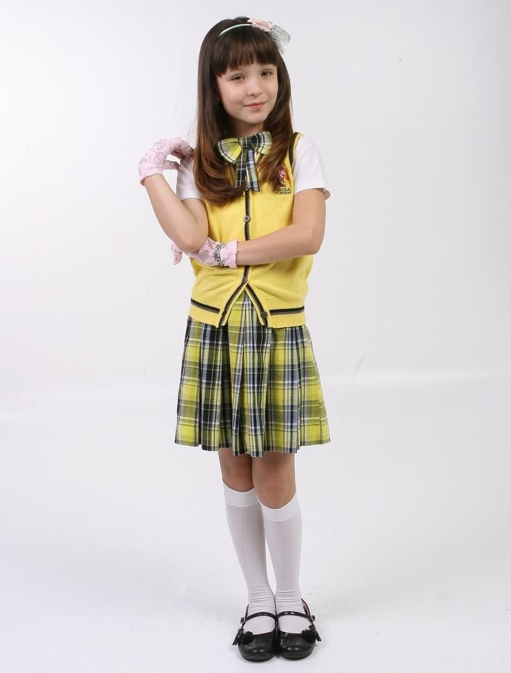 Menina com uniforme xadrez amarelo e preto, usando uma tiara e meias brancas, lembrando estilo de novelas.