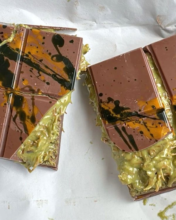 Chocolate artístico com recheio cremoso e detalhes em verde, preto e amarelo, típico de Dubai.