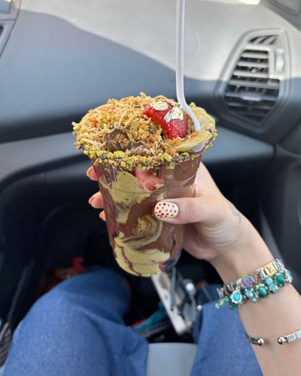 Sobremesa com camadas de chocolate, morangos e cobertura dourada em um carro.