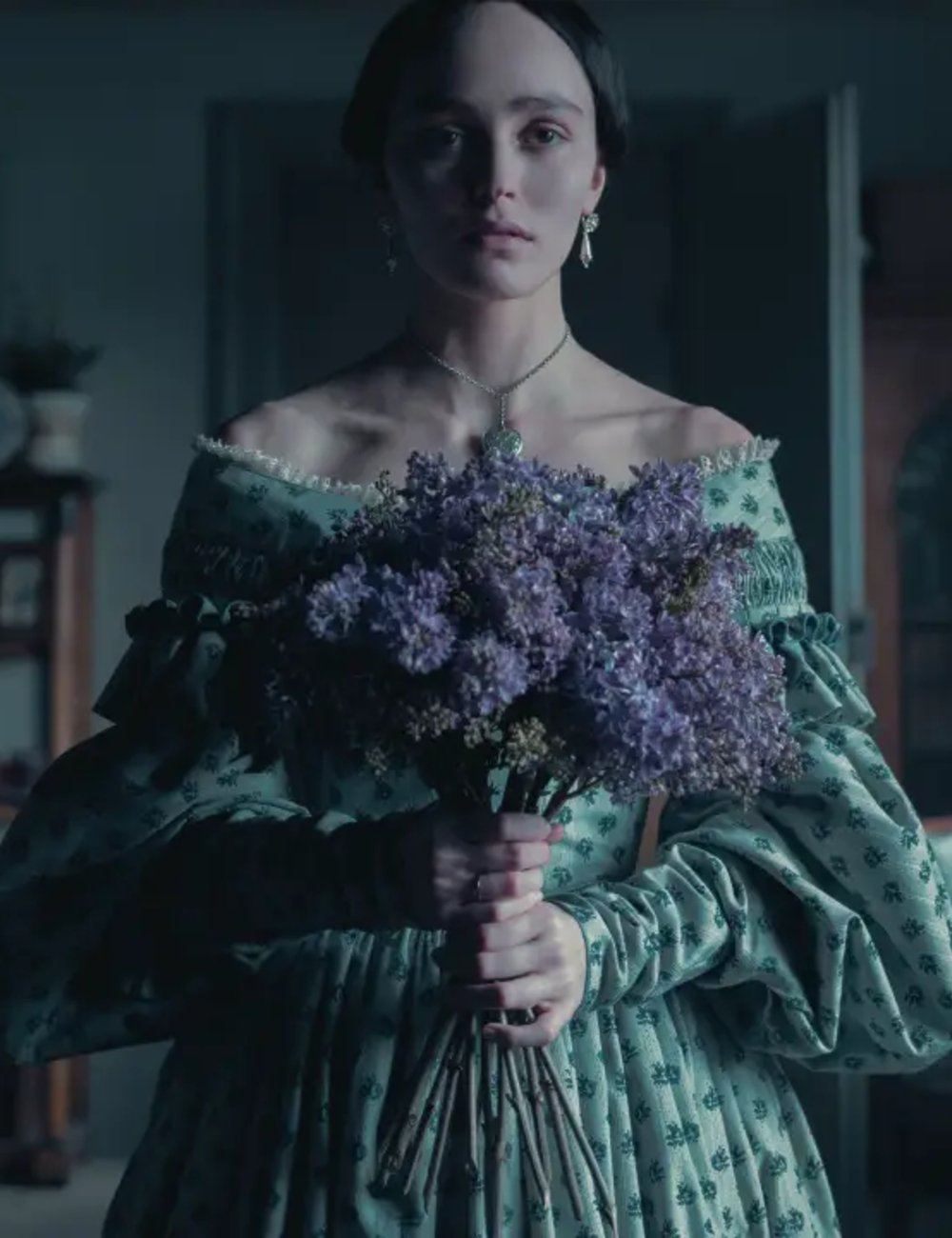 Moça em vestido verde vintage segura buquê de flores lilases, evocando estilo medieval core.