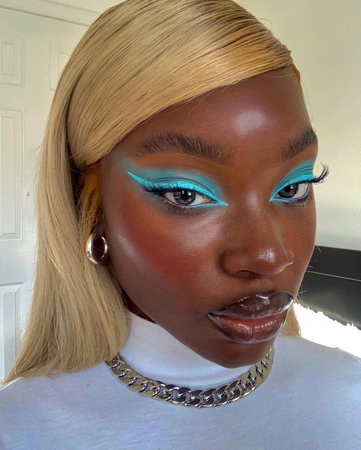 Maquiagem ousada em tons de azul, destacando olhos e lábios. A elegância sugere o uso dos melhores lápis de olho.