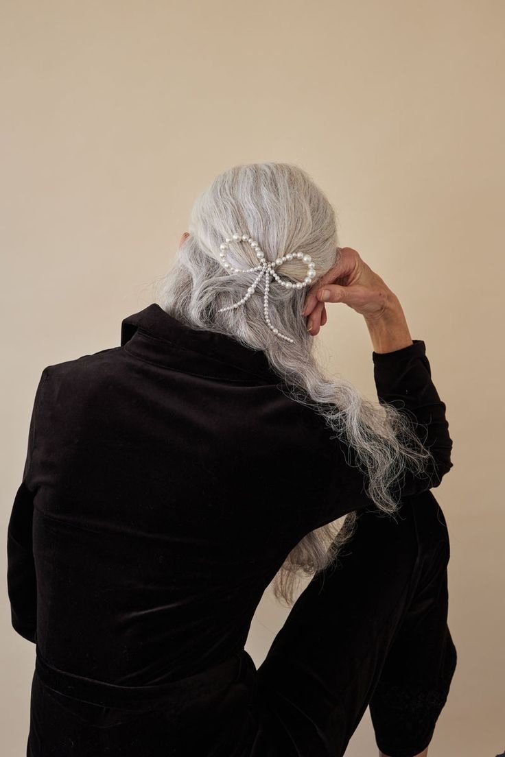 Cabelo grisalho adornado com laço de pérolas, destacando um dos penteados com laços mais elegante.