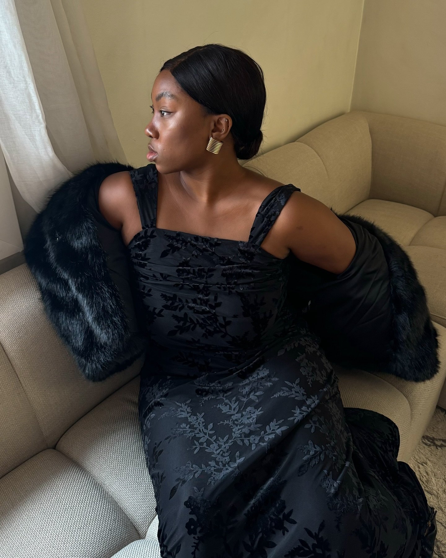 Mulher com vestido preto elegante e jaqueta de pele, ideal para vestido para casamento no inverno.