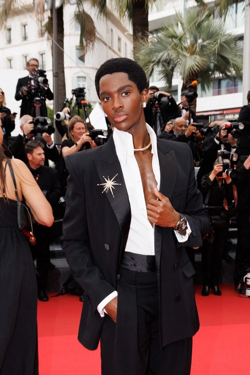 Elegante traje preto com broche brilhante destacado no Festival de Cannes 2025.