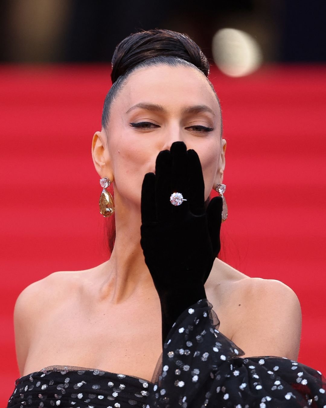 Celebridade no tapete vermelho com luvas pretas e brincos brilhantes. Acessórios elegantes no Festival de Cannes 2025.
