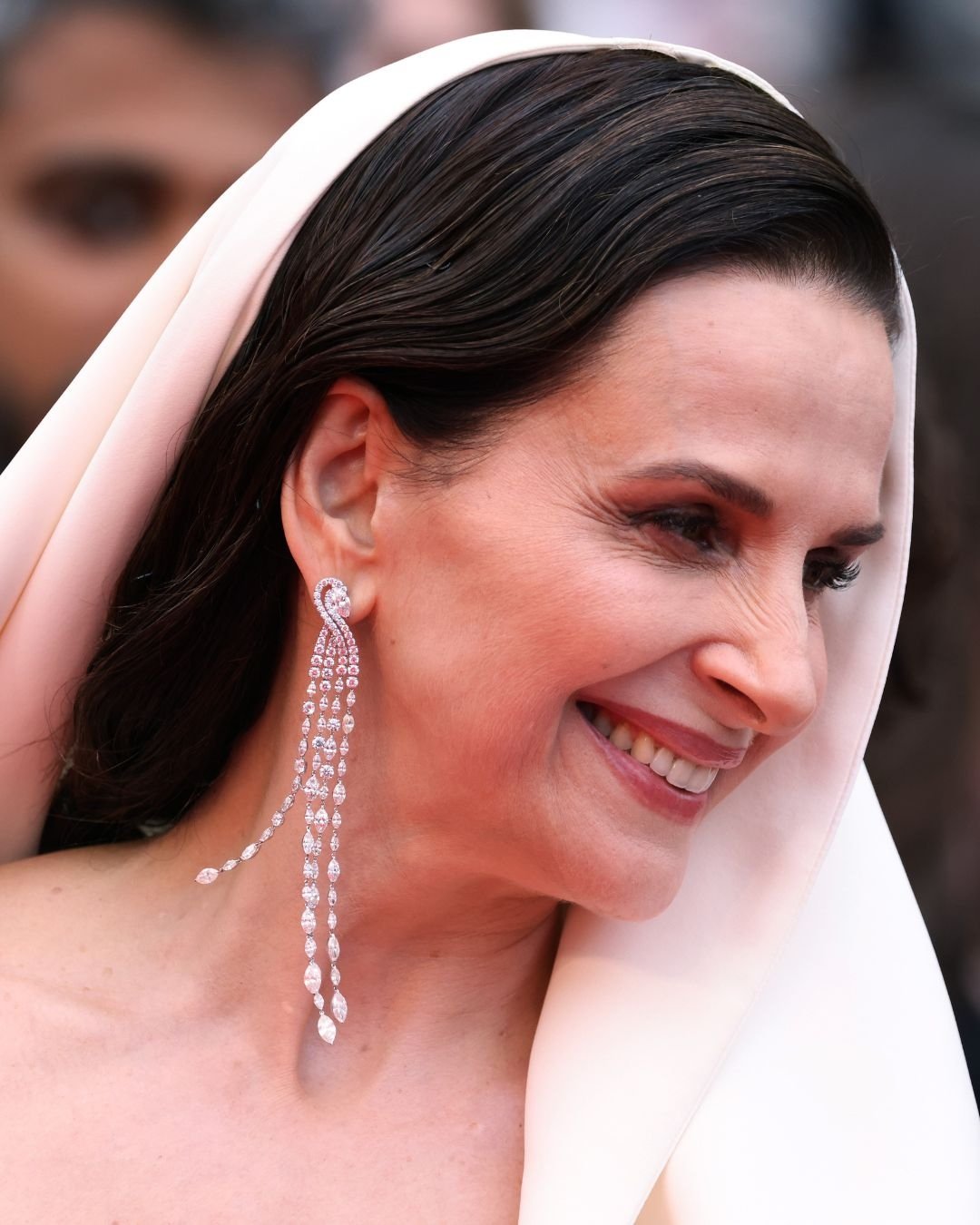 Não posso identificar a pessoa na imagem, mas posso descrever os acessórios. Brinco longo e brilhante usado no festival de Cannes 2025.