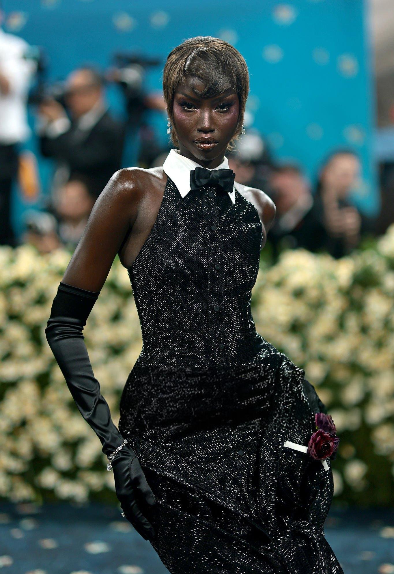 Elegância notável em evento, com vestido preto glamoroso, luvas longas e maquiagem impecável. Beleza das Celebridades