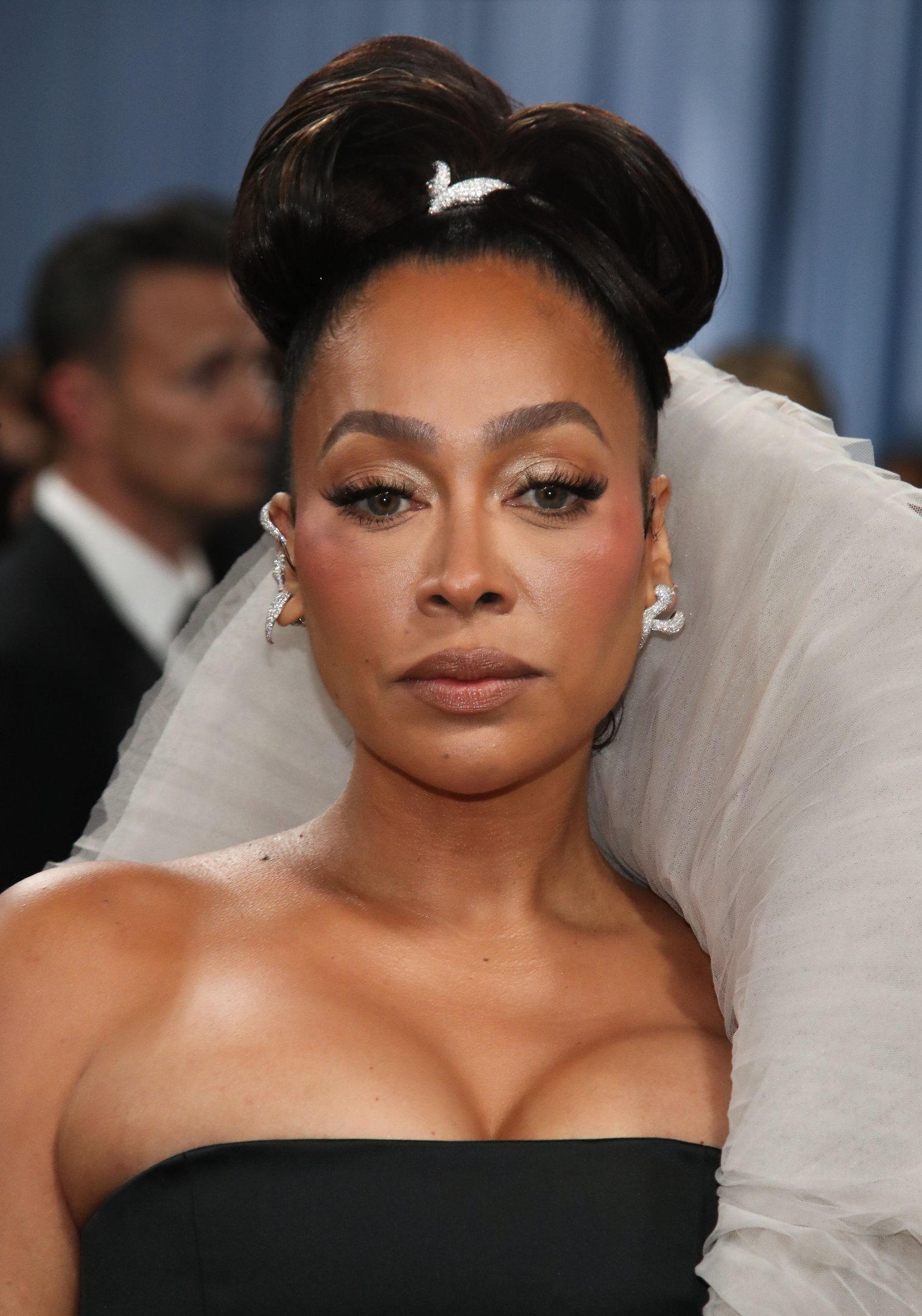 Pessoa com maquiagem elegante, penteado estiloso e vestido glamouroso, representando a sofisticação no evento. Beleza das celebridades