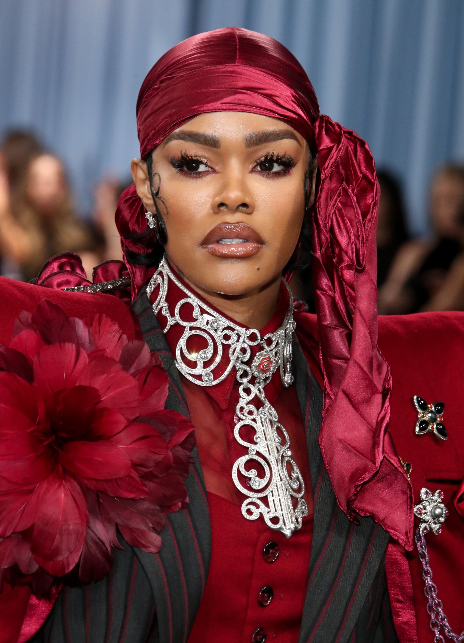 Pessoa em traje vermelho elegante com acessório prateado elaborad, destacando sua presença marcante e beleza luxuosa. Beleza das celebridades.