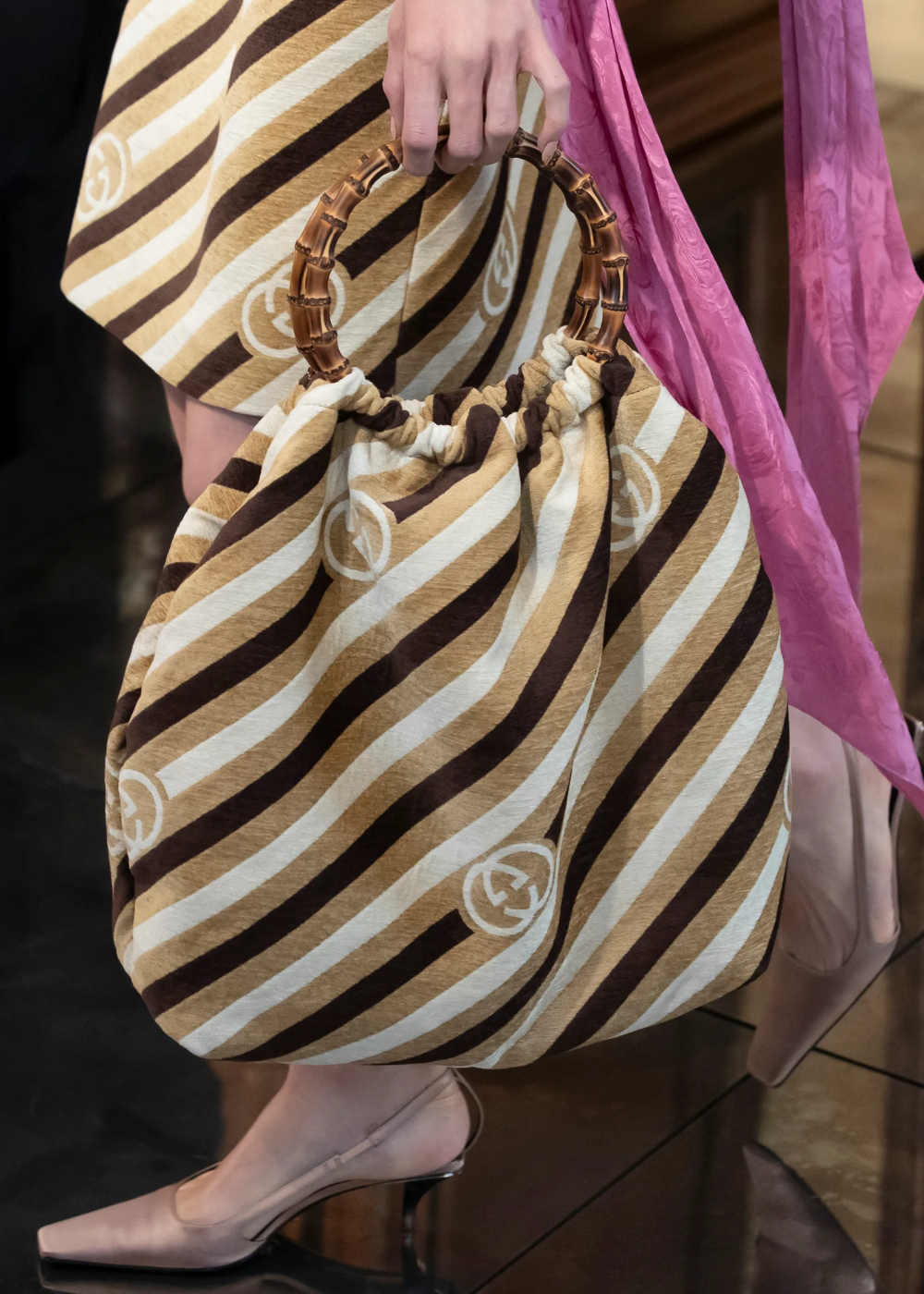 Bolsa com estampa listrada marrom e bege, alça de madeira, compõe look feminino estiloso.