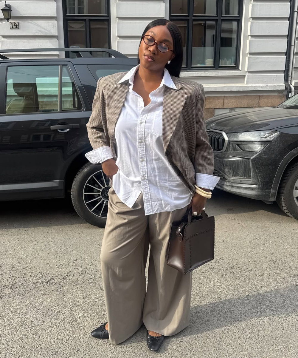 Mulher veste blazer e camisa branca, combinando com calças para trabalhar bege e sapatilhas pretas.