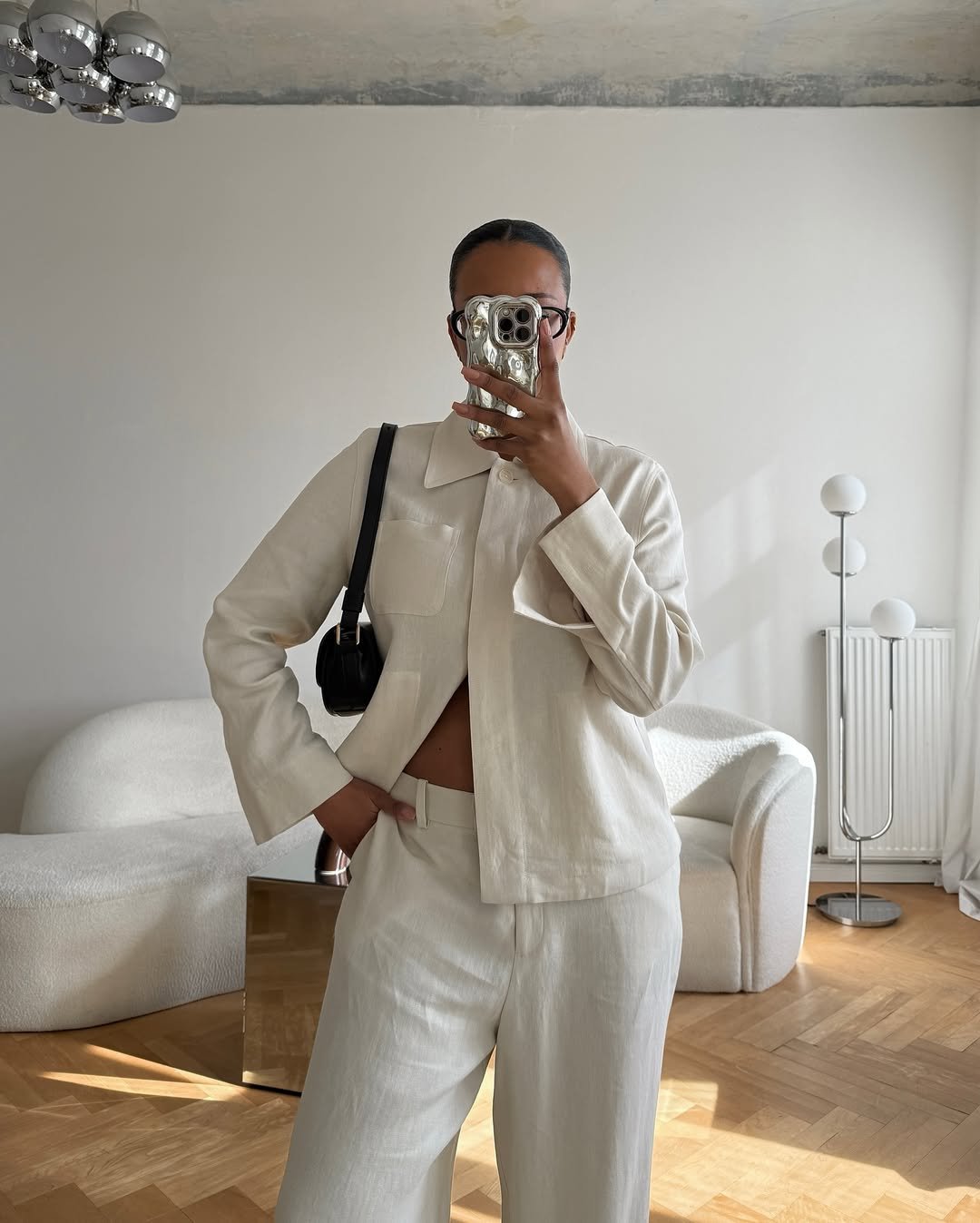 Pessoa com camisa branca feminina em ambiente moderno, segurando celular na frente do rosto.