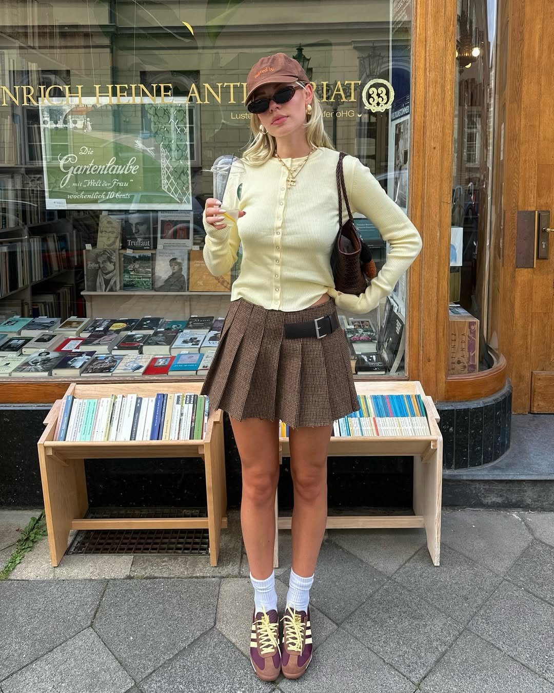 Pessoa com saia marrom e blusa amarela, em frente a uma livraria. O amarelo e o marrom criam um contraste harmonioso.