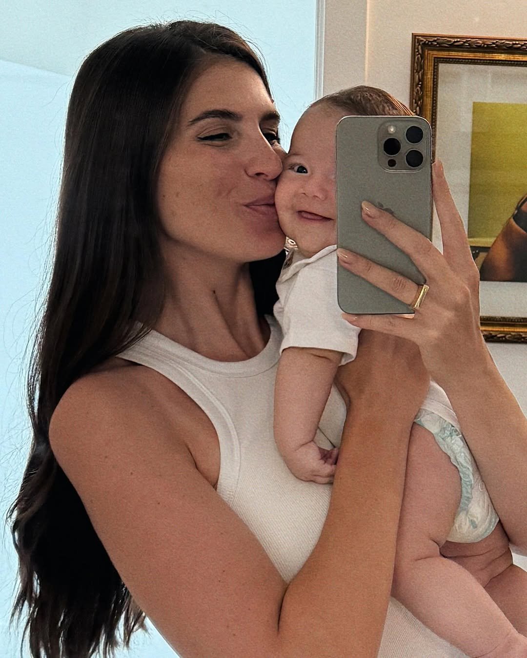 Mulher segurando bebê no colo, sorrindo em um momento de ternura que representa a maternidade.