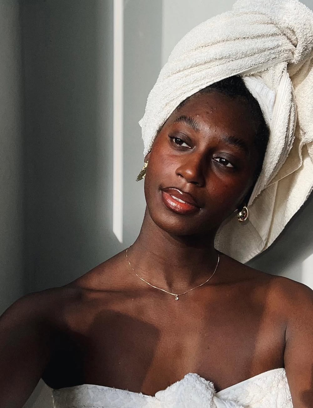 modelo posa com toalha no cabelo e pele com algumas espinhas