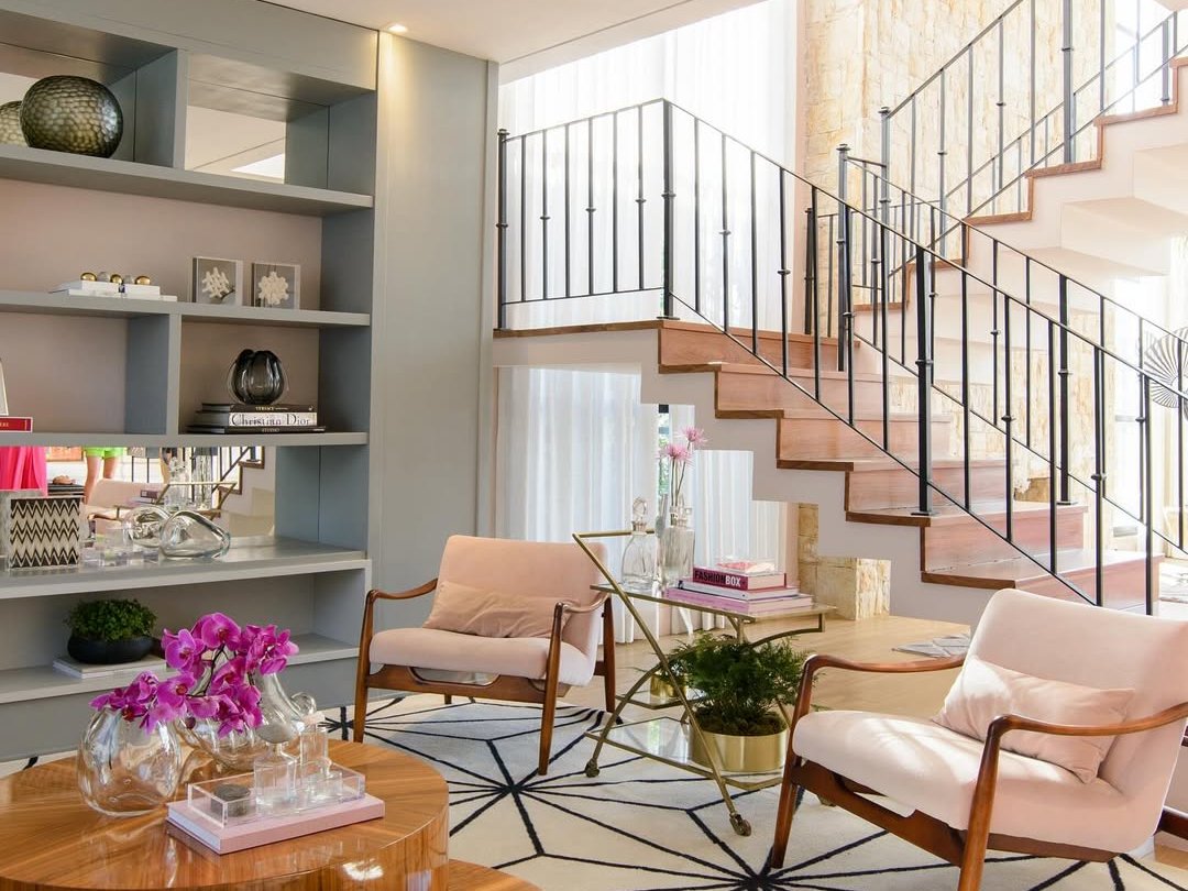 Sala de estar elegante com estante na decoração ao lado de escada moderna e cadeiras confortáveis.