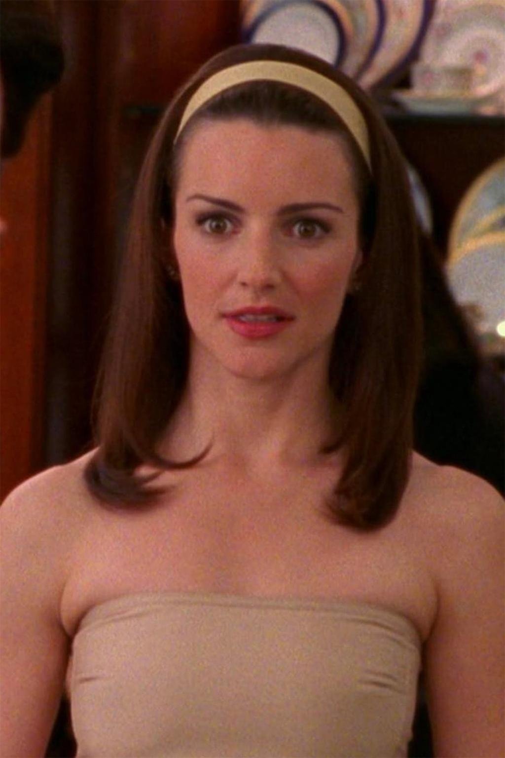 Mulher com cabelo liso e longo, usando uma faixa e blusa tomara que caia, estilo sofisticado de Charlotte York.