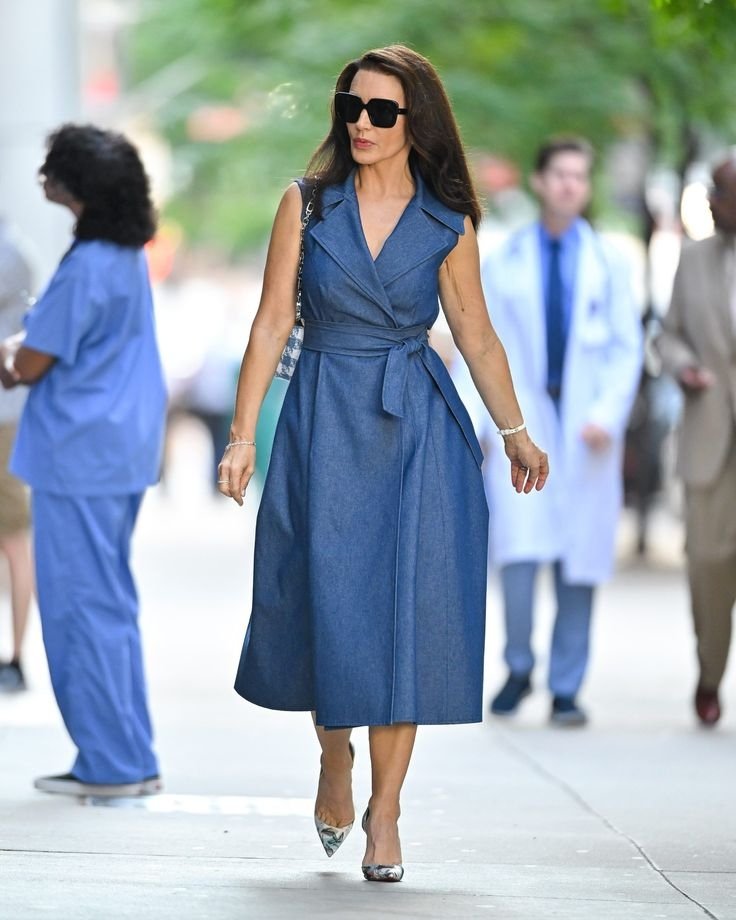 Mulher elegante em vestido jeans e sapatos prateados, exibe um visual clássico e sofisticado.