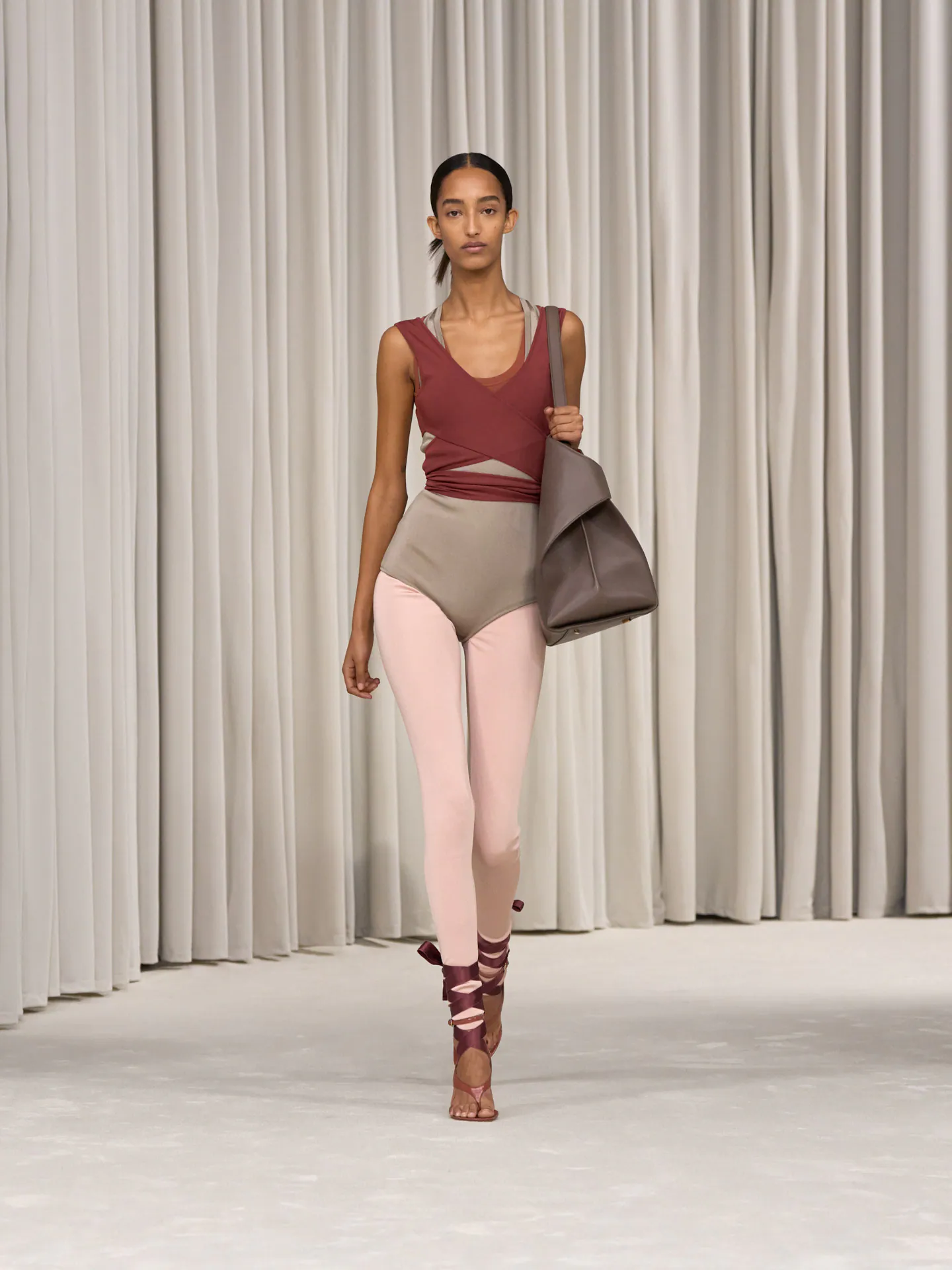 Modelo caminha na passarela usando roupa em tons neutros, destacando tendência de beleza minimalista.