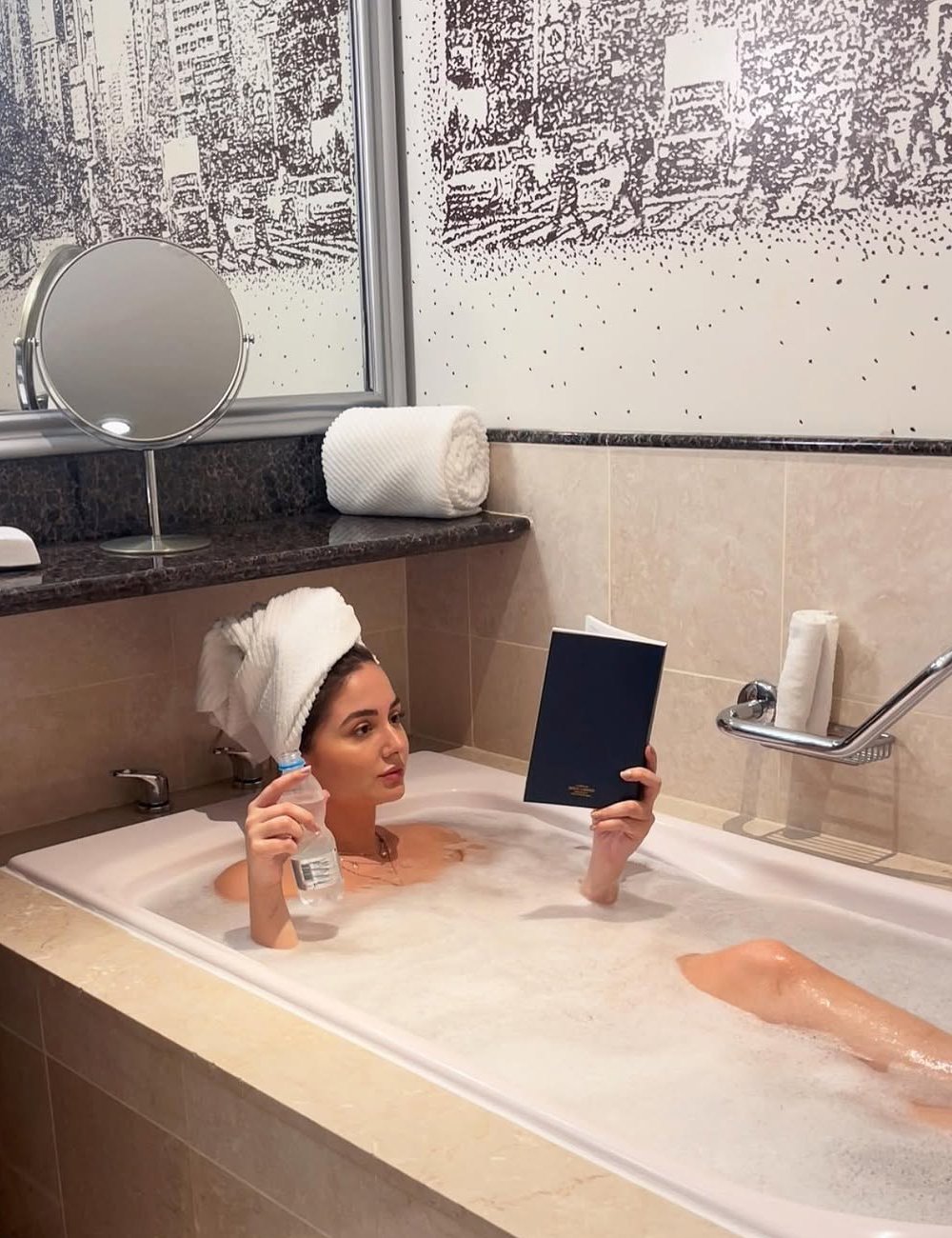 Modelo relaxa na banheira enquanto faz skincare