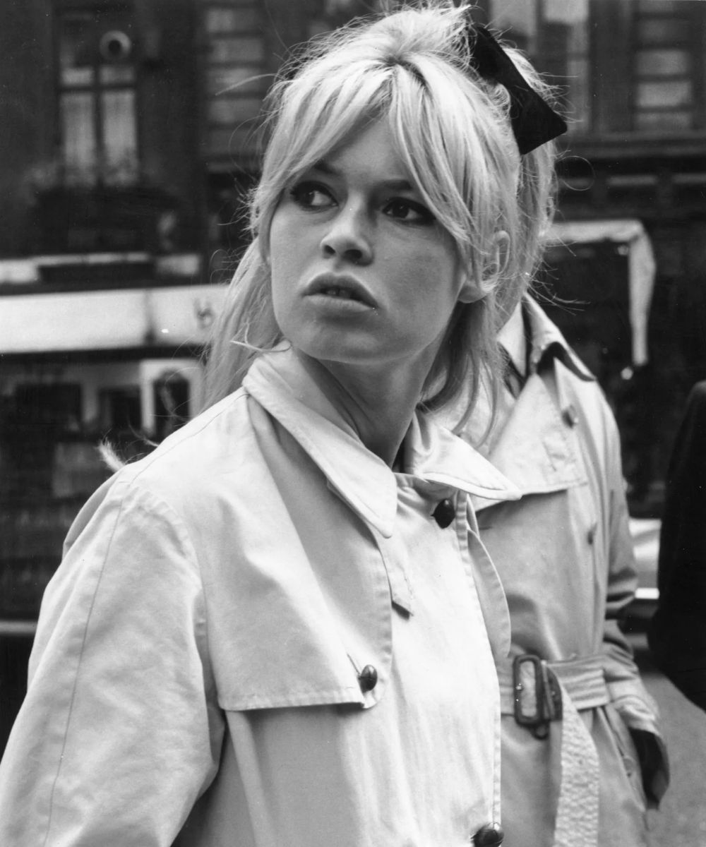 Jovem de cabelo loiro com penteado típico, incluindo franja icônica ao estilo da Brigitte Bardot.