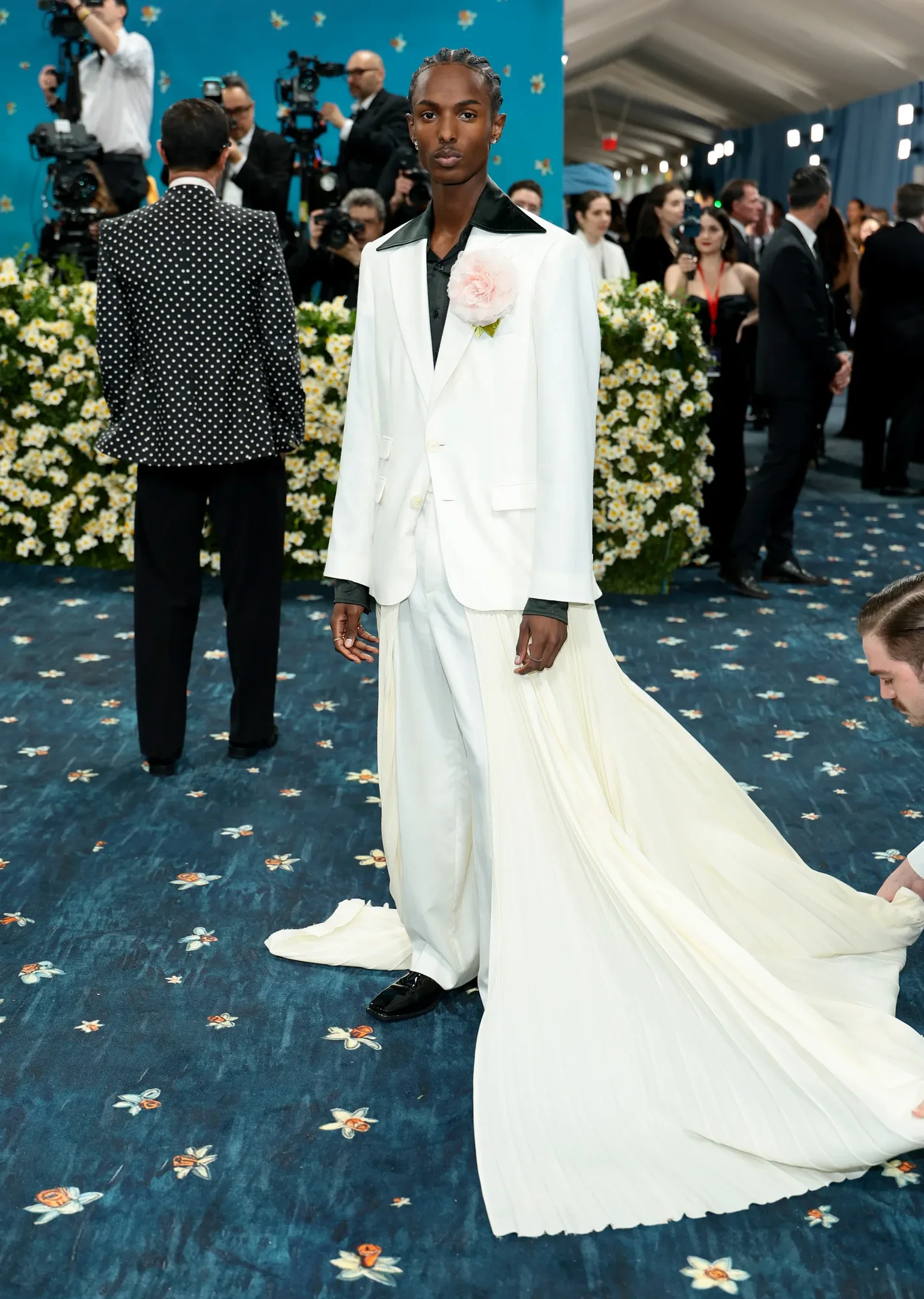 Homem em traje branco com cauda e rosa no terno em evento formal. Looks masculinos.