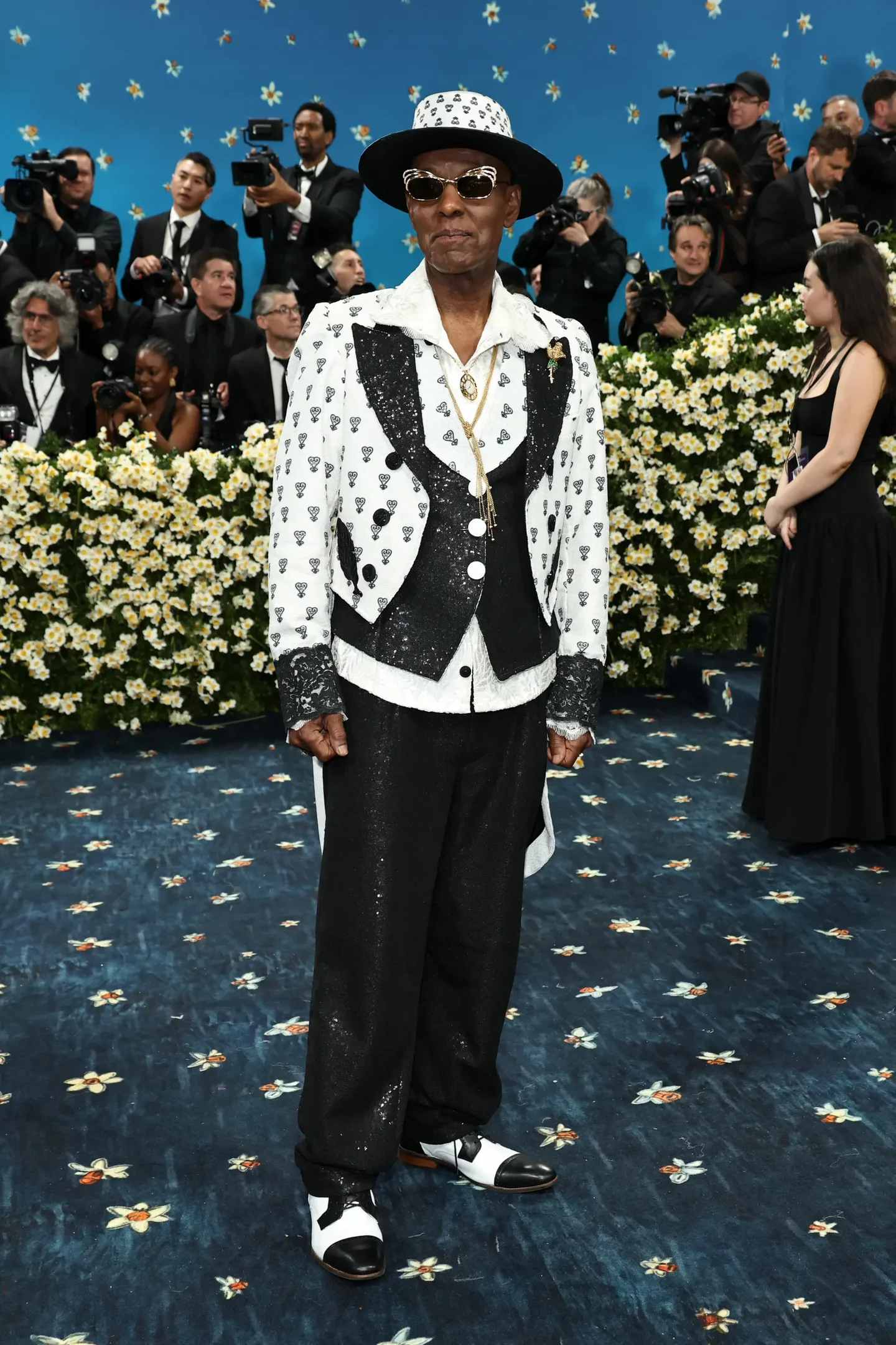 Homem em traje elegante preto e branco com padrões, chapéu e óculos de sol. Looks masculinos sofisticados.