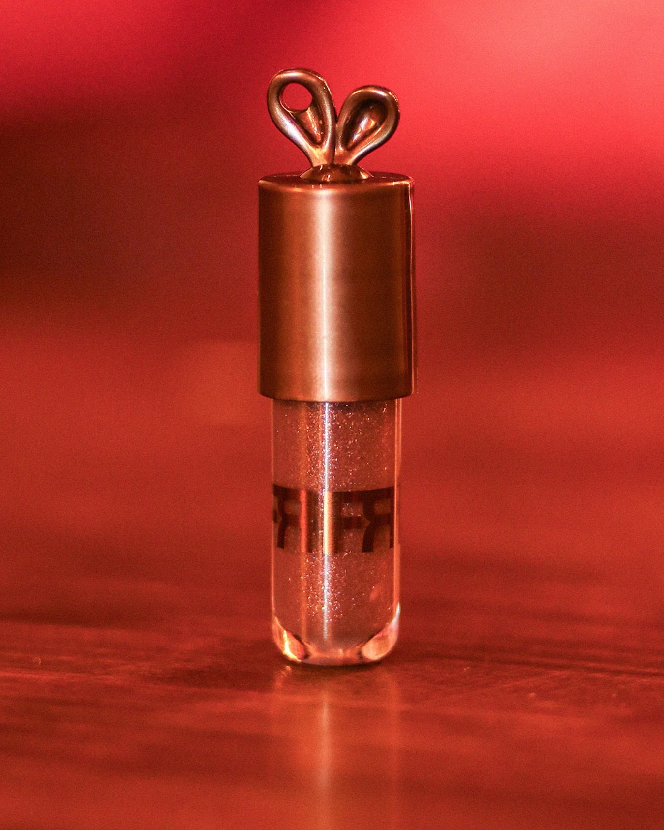 Brilho labial cintilante com tampa dourada decorada com orelhas de coelho.
