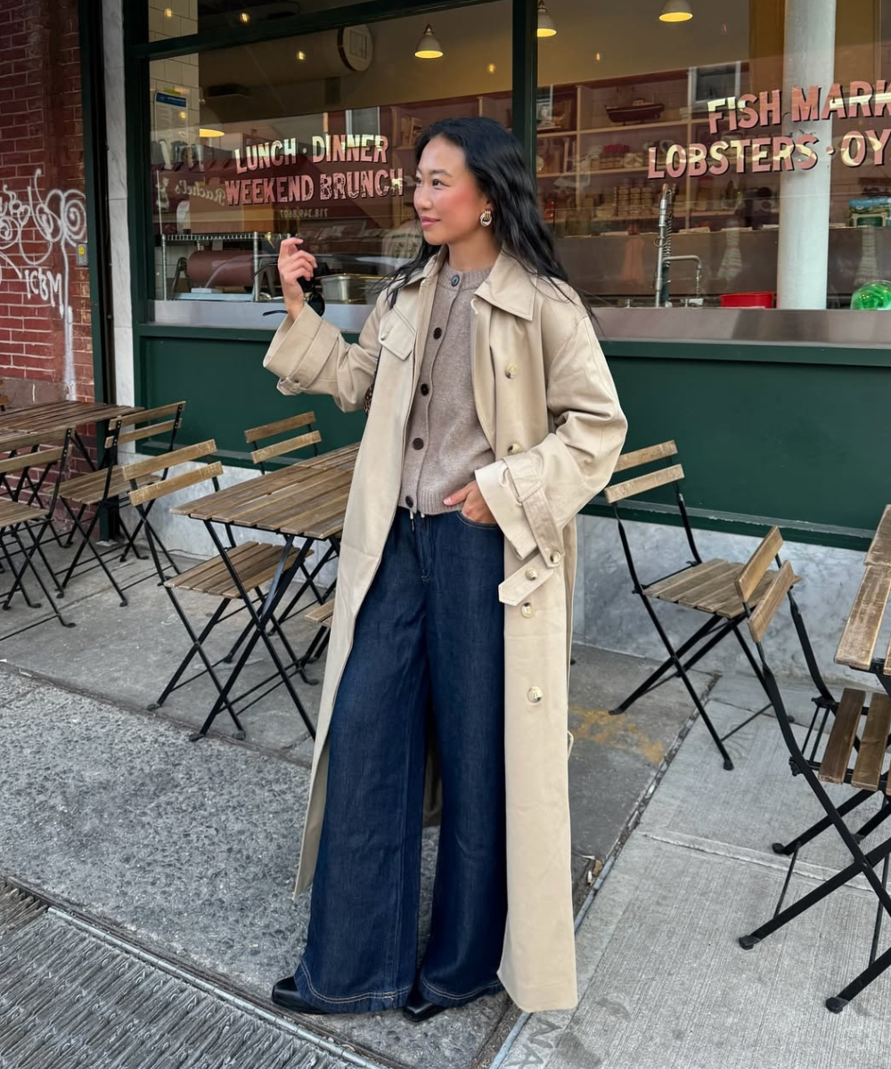 Mulher usando cardigã e trench coat, em frente a um restaurante, looks casual de outono.