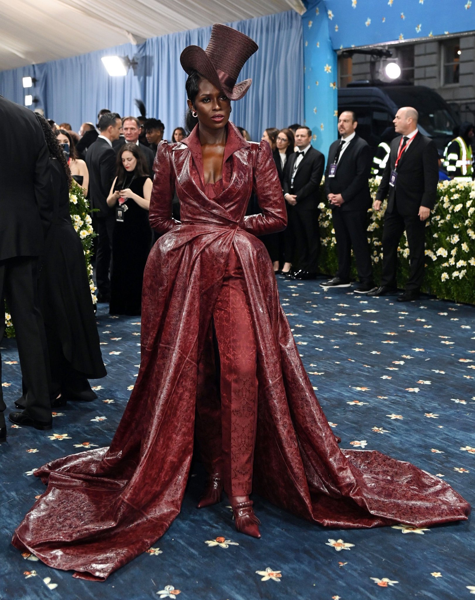 Celebridade em evento de gala, vestindo traje marrom texturizado e chapéu alto, posando no Met Gala 2025.