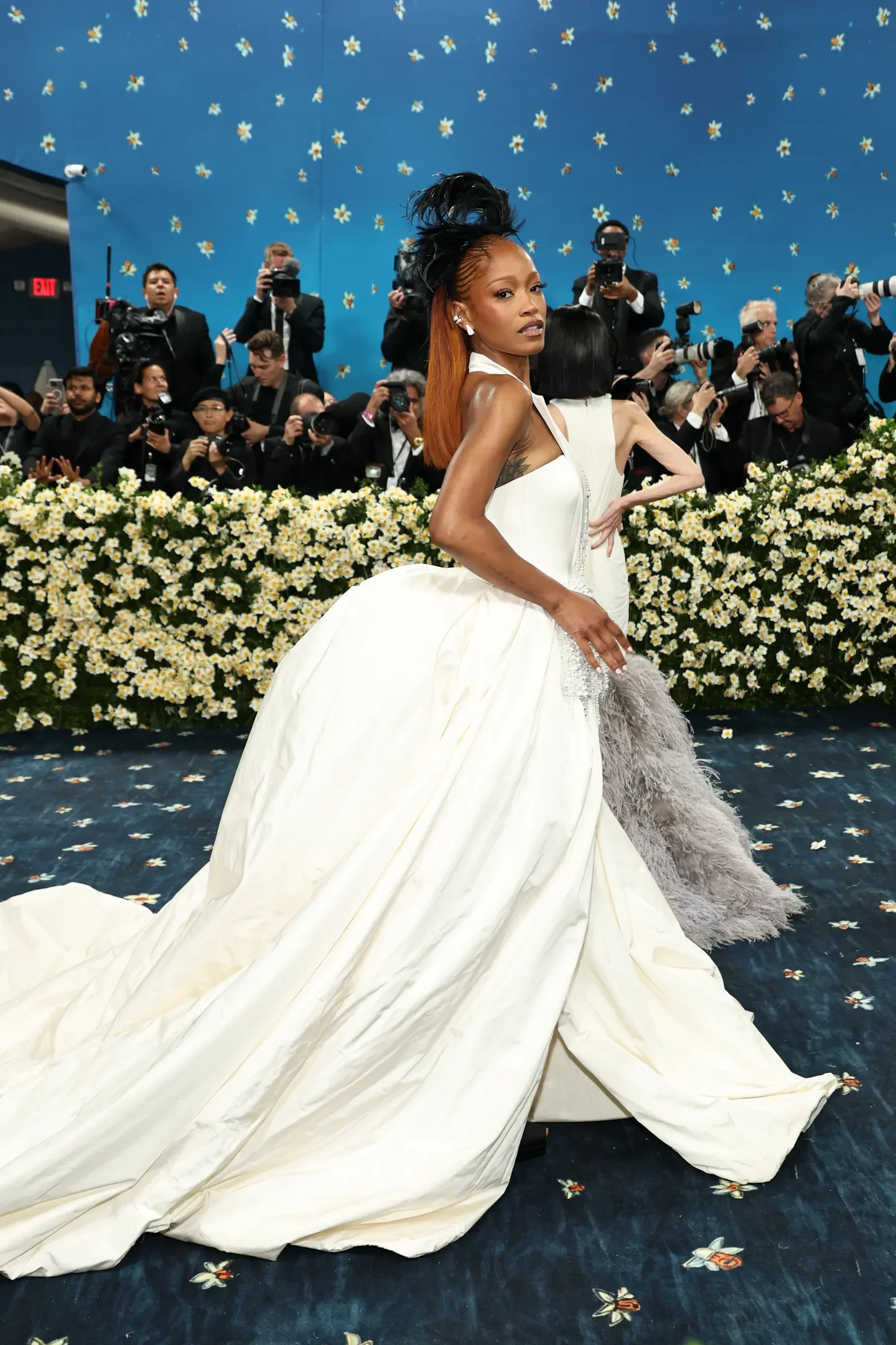 Celebridade deslumbrante em vestido branco volumoso e detalhes em penas no Met Gala 2025, cercada por fotógrafos.