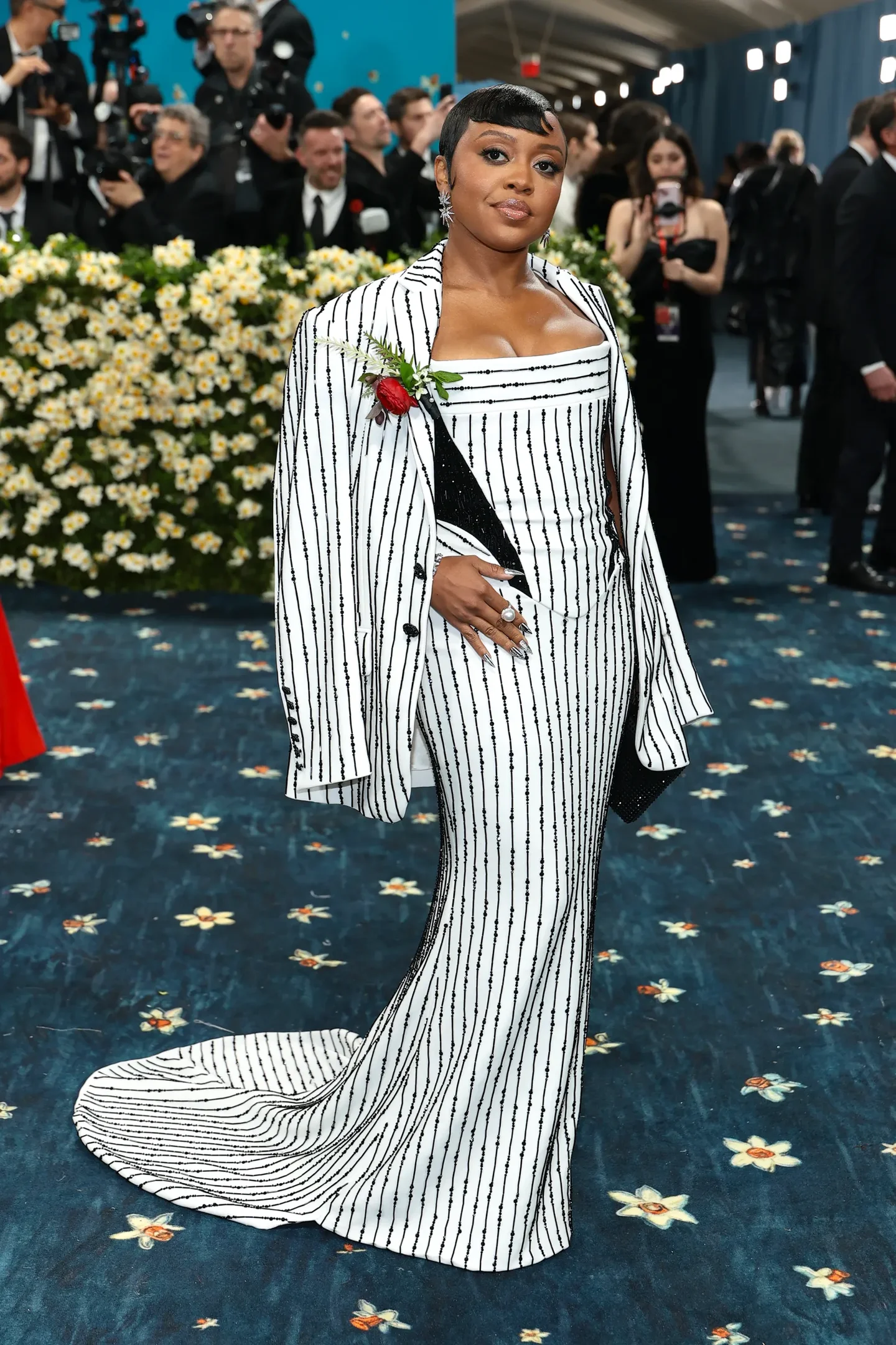 Vestido longo branco com padrão risca de giz preto, acompanhado de blusa e casaco combinando, usado por mulher em evento.