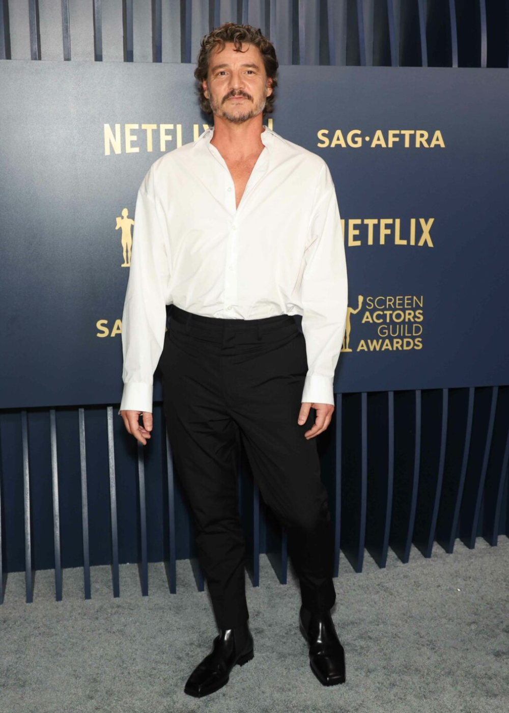 Homem de camisa branca e calças pretas em evento da Netflix e SAG-AFTRA.