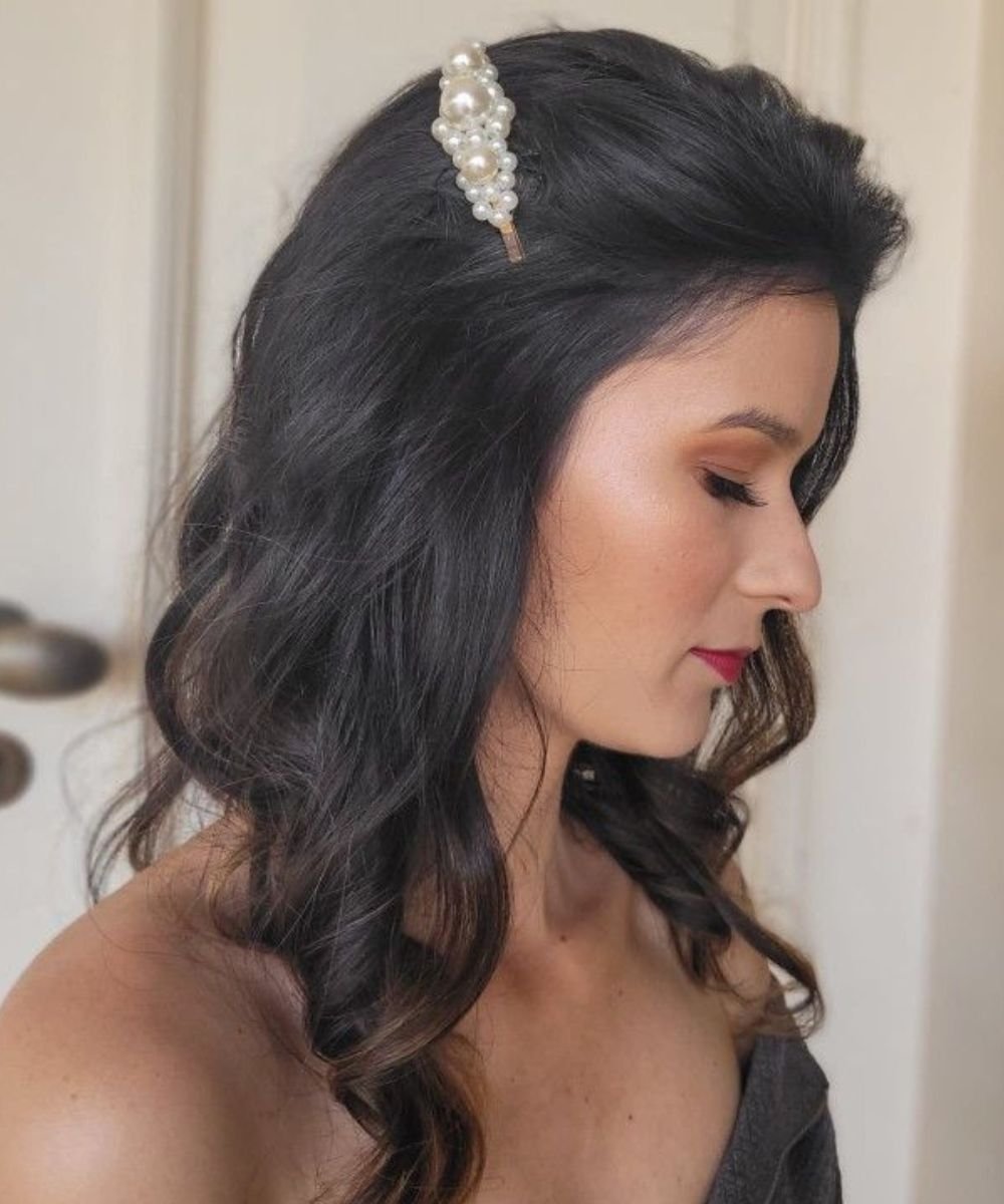 Cabelo solto com ondas suaves e presilha de pérolas, exemplo de penteados fáceis.