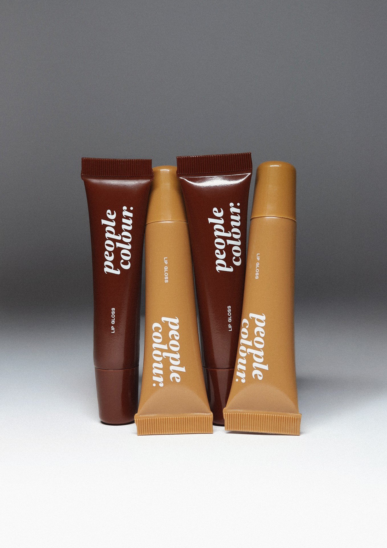 Tubos de gloss labial nas cores marrom e bege exibindo a marca