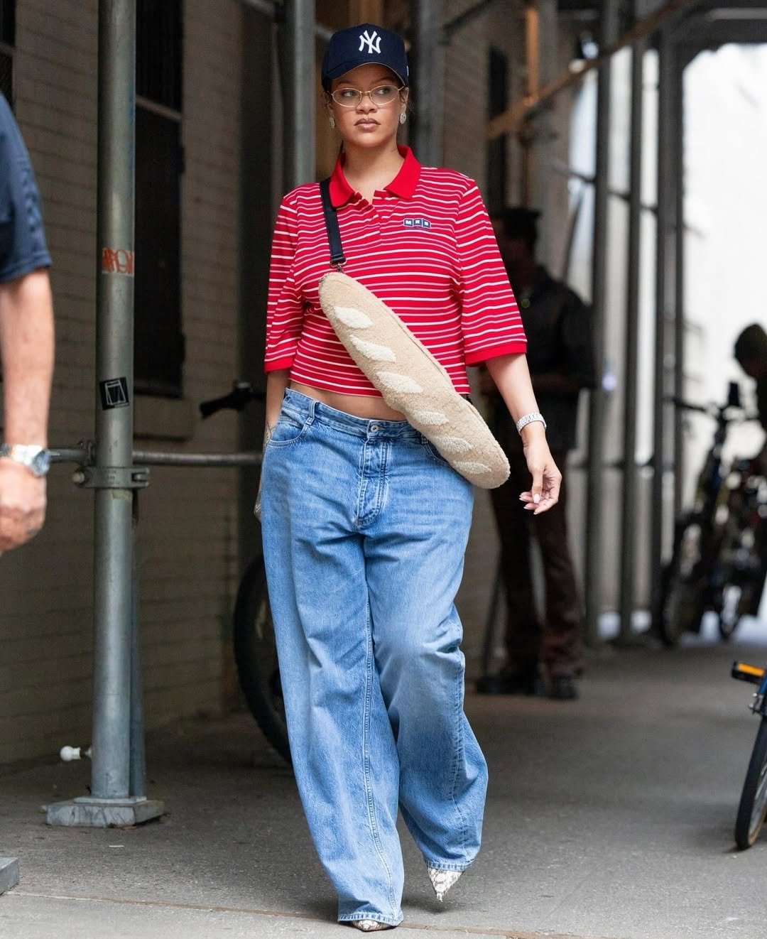 Pessoa usa camisa polo tendência listrada vermelha e jeans largos. Acessórios incluem boné e bolsa criativa. Tendência urbana.