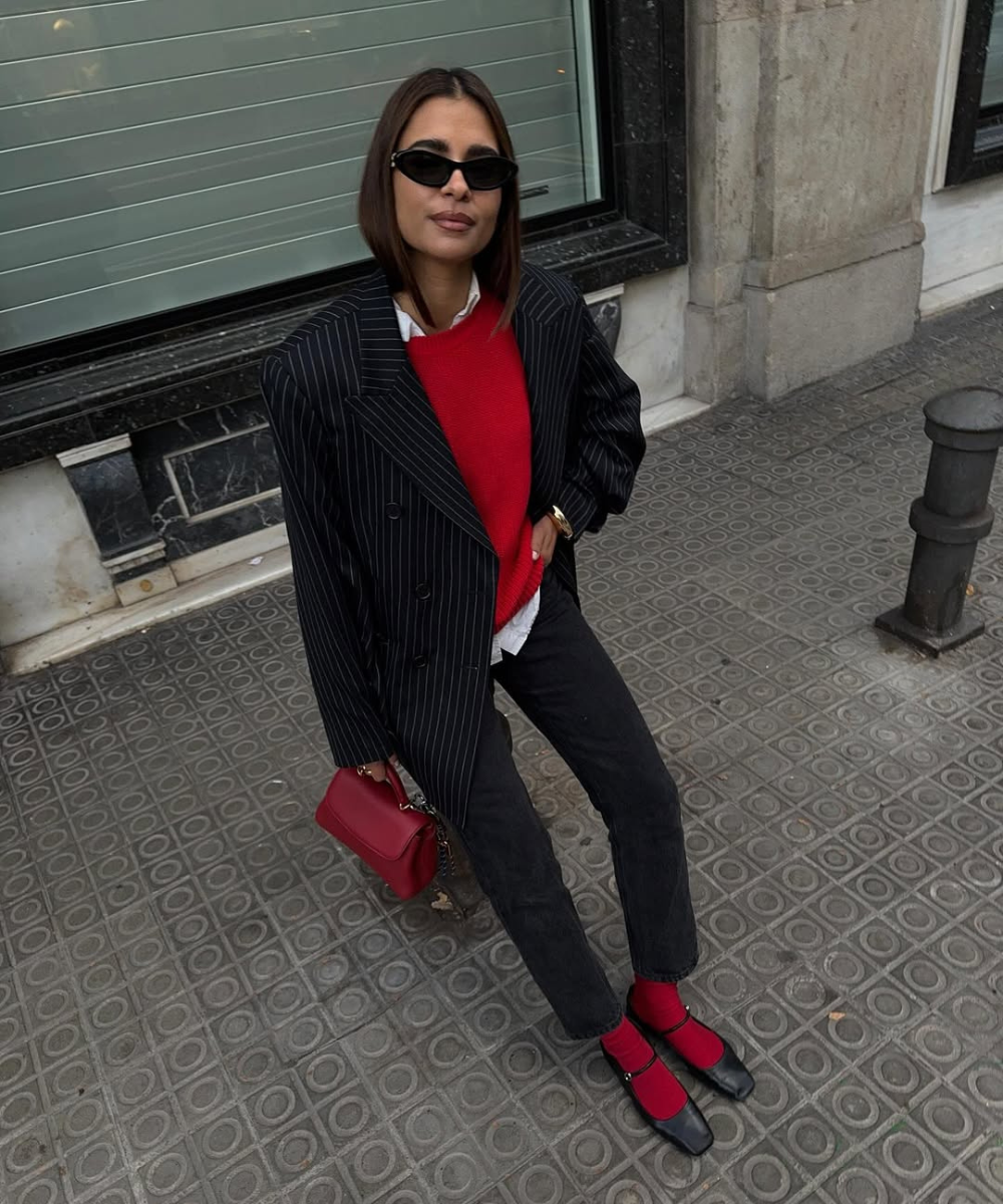Pessoa usando blazer listrado, suéter vermelho e sapatilhas elegantes pretas com meias da mesma cor do suéter.