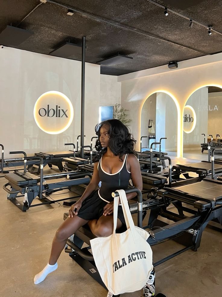 Pessoa sentada em academia elegante, usando roupas de treino e segurando bolsa. Ambiente moderno sugere busca por reduzir sarcopenia.