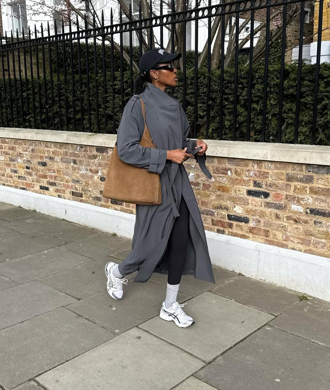 influenciadora posando com legging, boné e trench coat, look do estilo esportivo