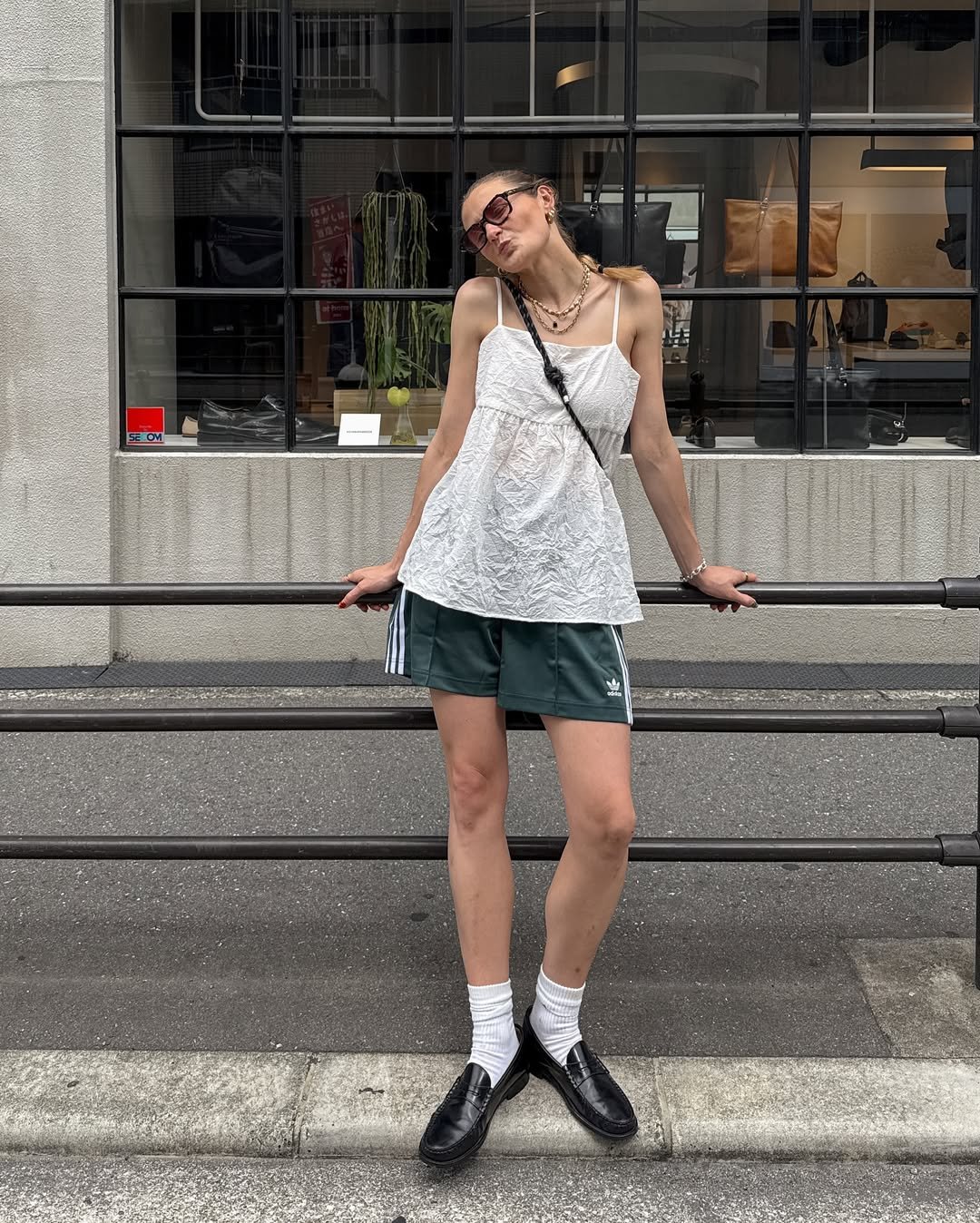 influenciadora posando para a foto usando shorts do estilo esportivo, blusa branca e mocassim com meia
