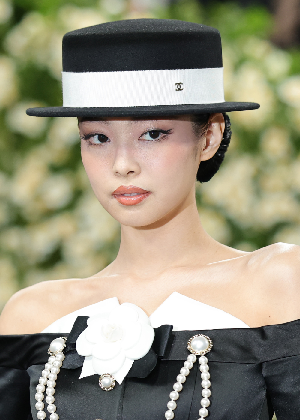 Pessoa usando chapéu preto e branco, com flor e pérolas. Look elegante no Met Gala 2025.
