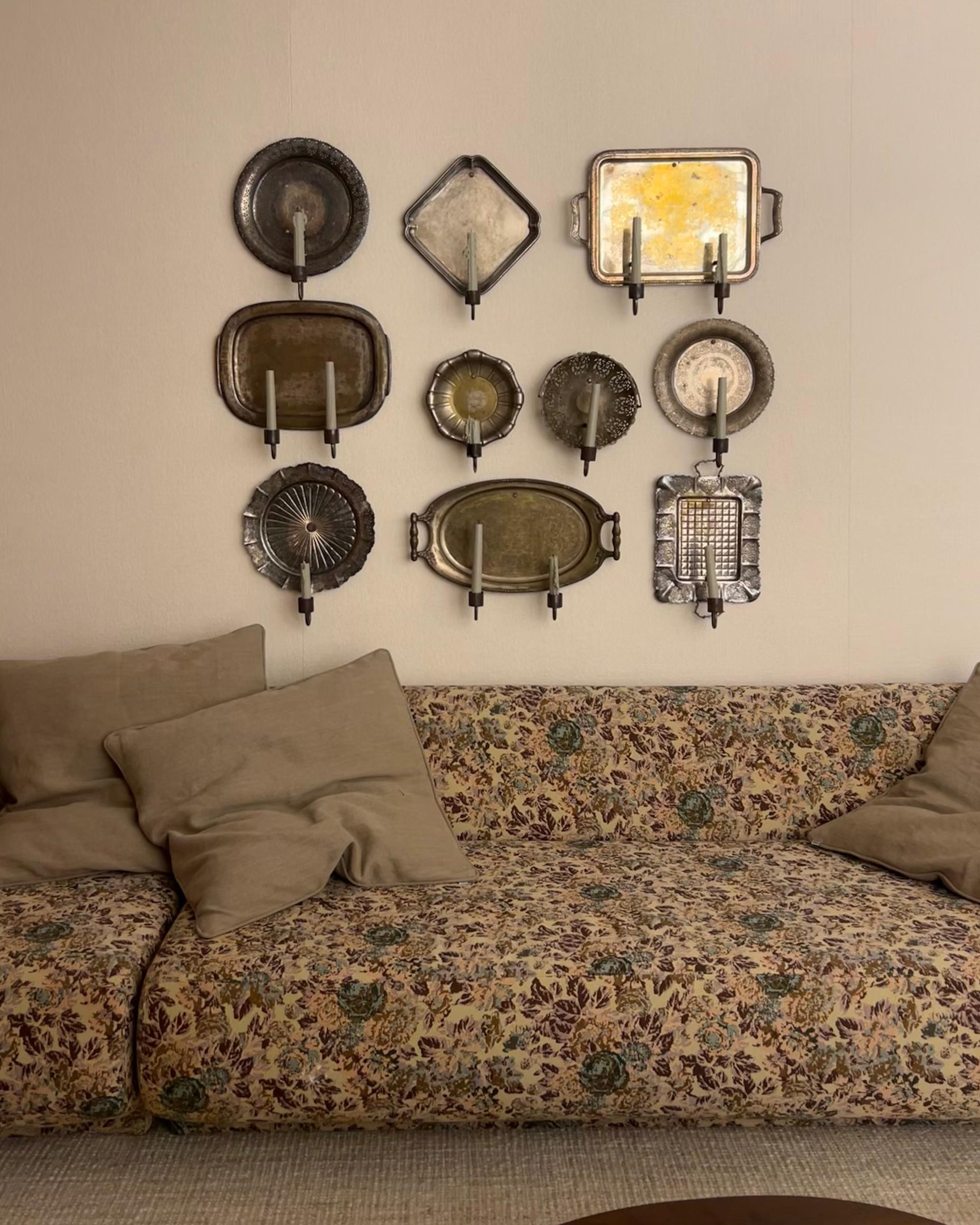 Placas decorativas emolduram parede acima de sofá floral. Estilo CASACOR 2025.