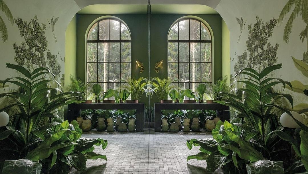 Ambiente sofisticado com plantas exuberantes e grandes janelas arqueadas destacando uma decoração inovadora da CASACOR 2025.