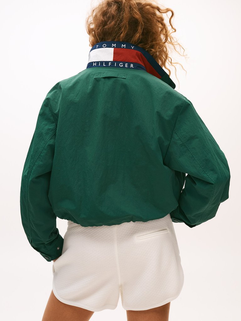 Casaco verde estilo fishermancore com gola estampada da Tommy Hilfiger, combinado com shorts brancos.